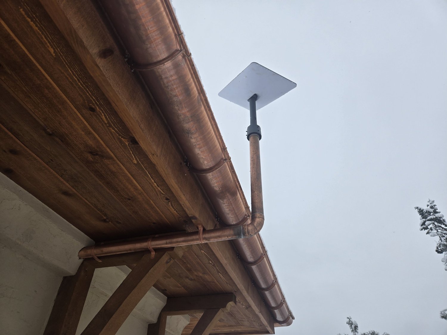 Copper gutter and roofline detail against an overcast sky